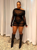 A woman stands in front of white curtains wearing a sheer black off-the-shoulder mini dress with long sleeves and matching fingerless gloves, paired with black pointed-toe knee-high boots.